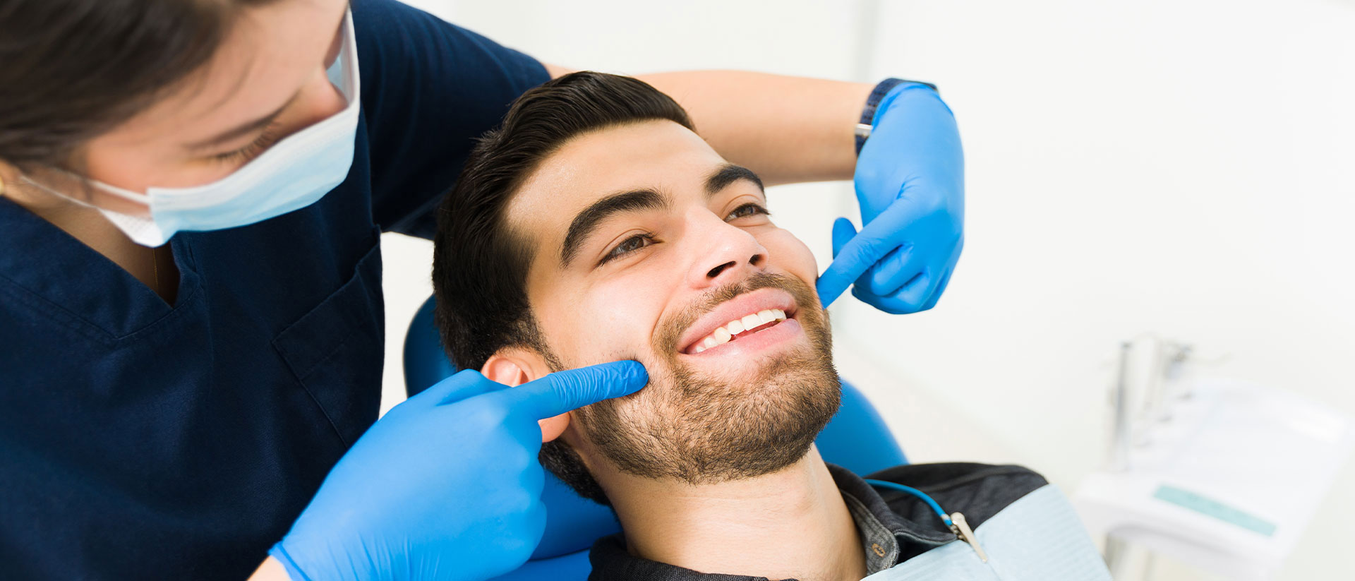 A dental professional performing a procedure on a patient s teeth while the patient smiles.