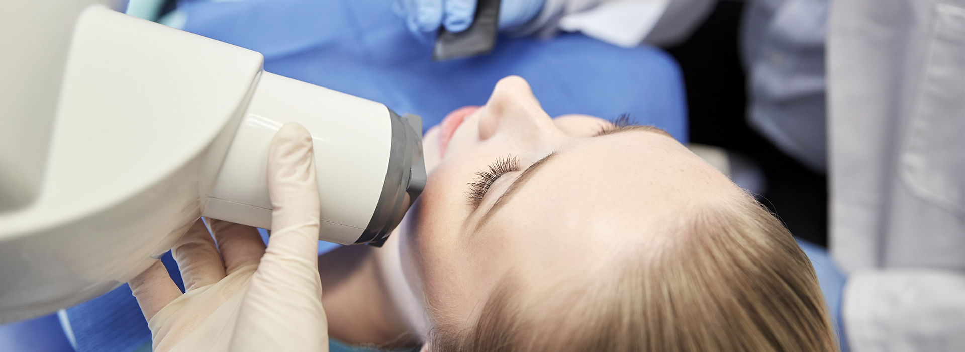 A woman is seated in a dental chair, receiving dental care.