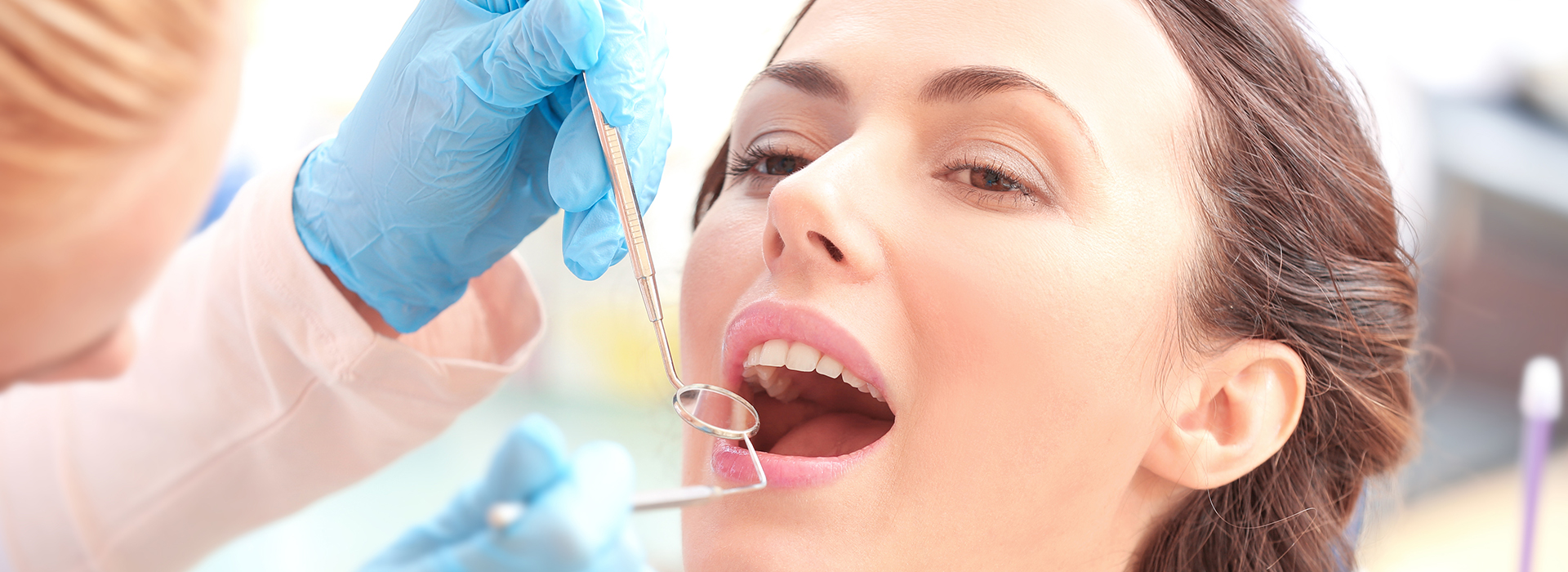 A dental hygienist is performing a teeth cleaning procedure on a patient in a dental office setting.