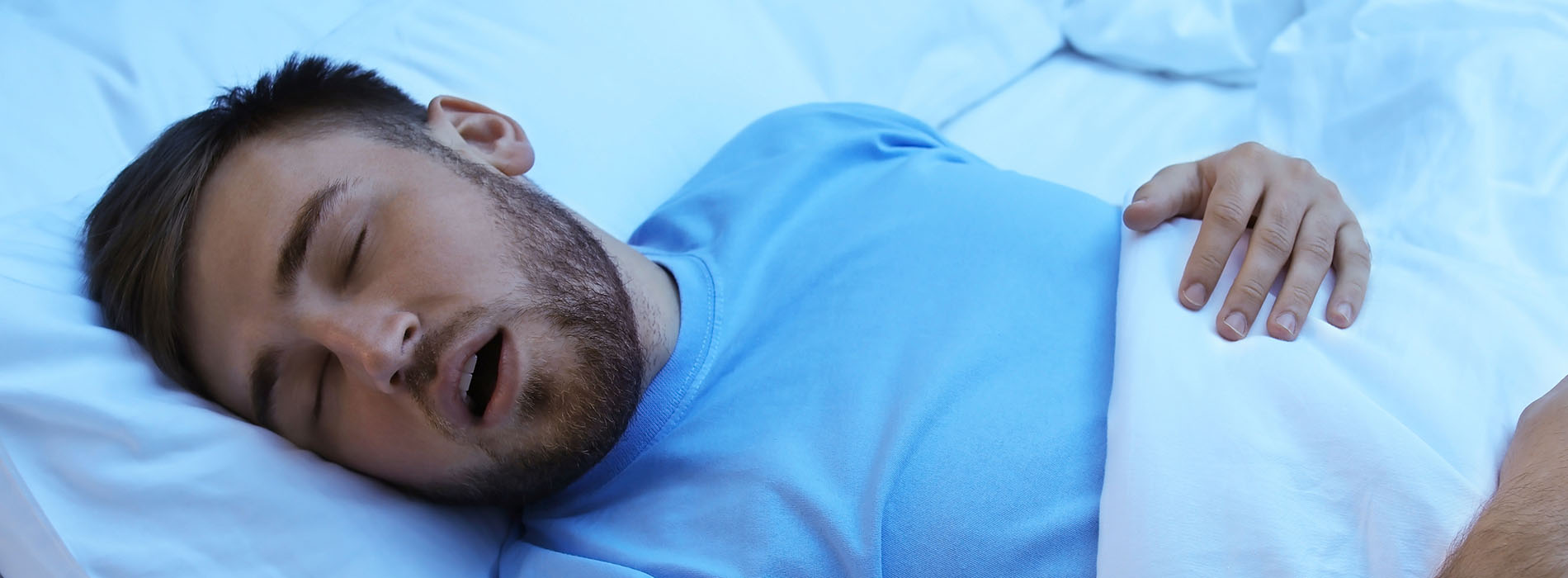 A man in a hospital bed, sleeping with his mouth open.