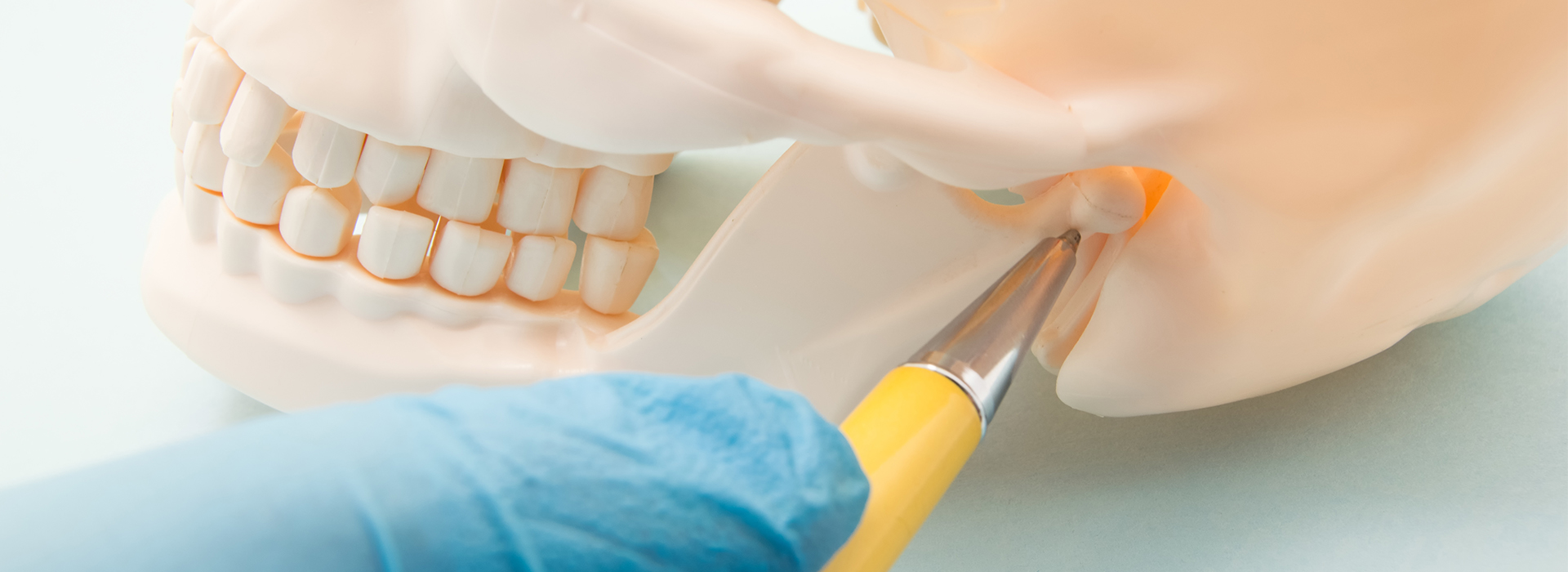 The image depicts a close-up of a person s teeth being worked on by a dental professional, with a toothbrush and dental tools visible in the process.