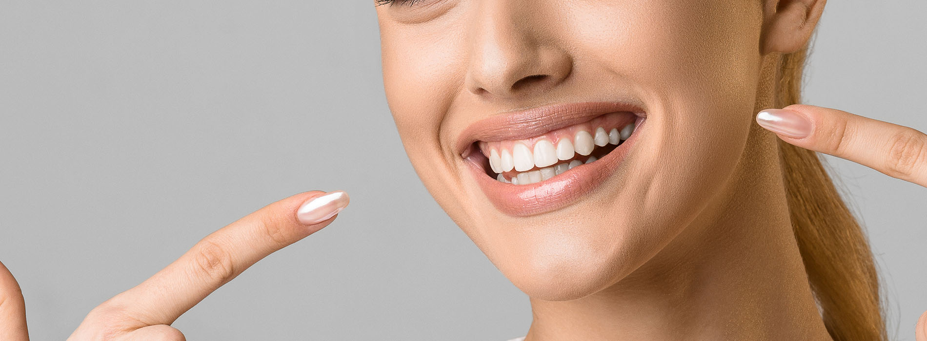 Smiling woman with hand on face, showcasing skincare product.