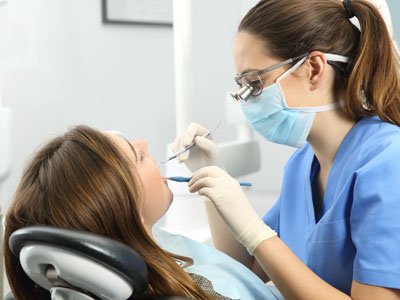 A dental hygienist is performing a teeth cleaning procedure on a patient in a dental office setting.