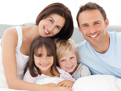 A family of four, including a man, woman, and two children, posing for a photo with smiles on their faces.