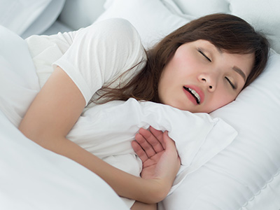 Woman sleeping in bed with eyes closed.