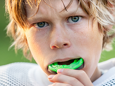 A young male athlete, with a determined expression, brushing his teeth on the field.