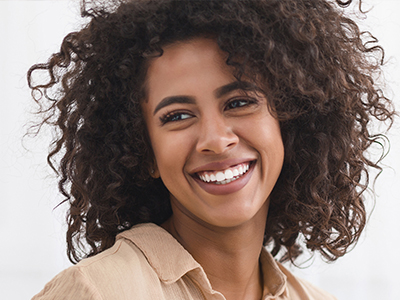 A woman with curly hair and a broad smile is the central focus of this image.